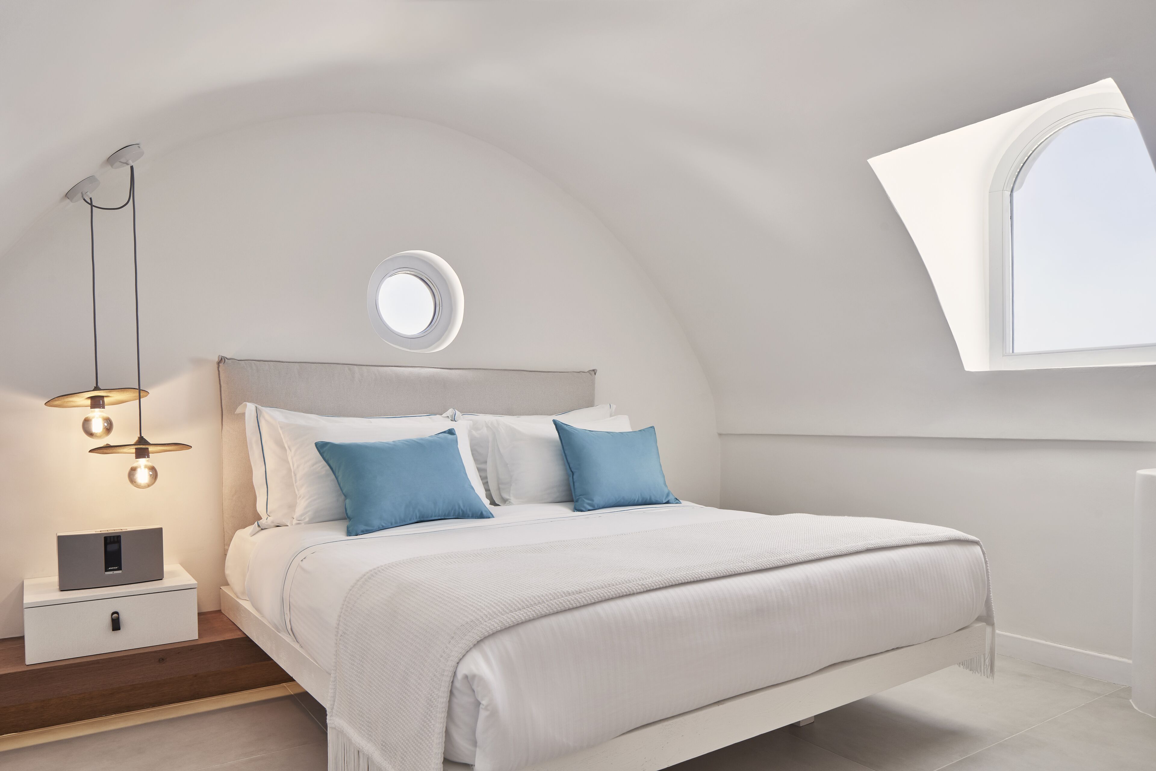 A modern bedroom with a bed, bedside table, and a window with a view.