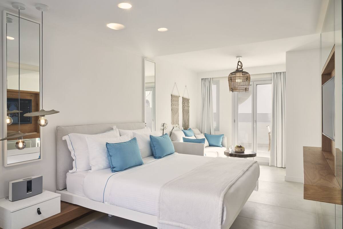 Une chambre à coucher moderne avec un grand lit, des tables de chevet, un miroir et un téléviseur.