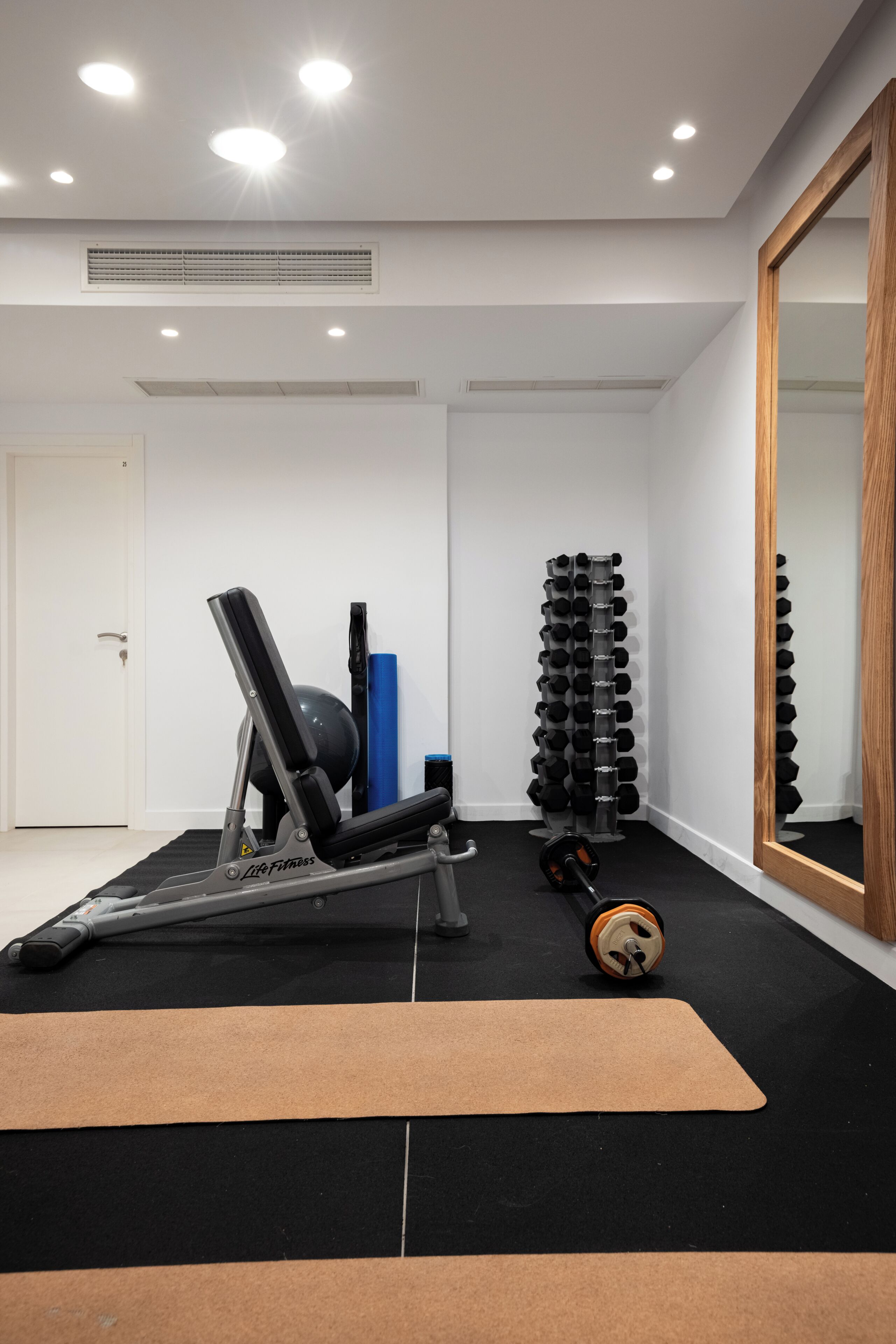 Un gimnasio con equipo de ejercicio, un espejo y una puerta.