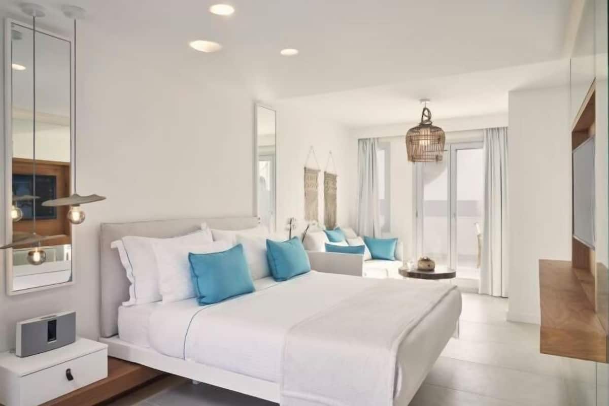 Une chambre moderne avec un grand lit, des tables de chevet, un miroir et un luminaire suspendu.