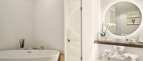 A modern bathroom with a freestanding bathtub, a glass-enclosed shower, a large mirror with a textured wall, and a vanity with a sink and towel storage.