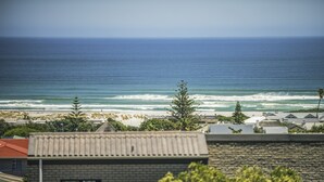 A coastal view with a beach, ocean waves, and buildings in the foreground. - Home with an Ocean view (Hermanus)