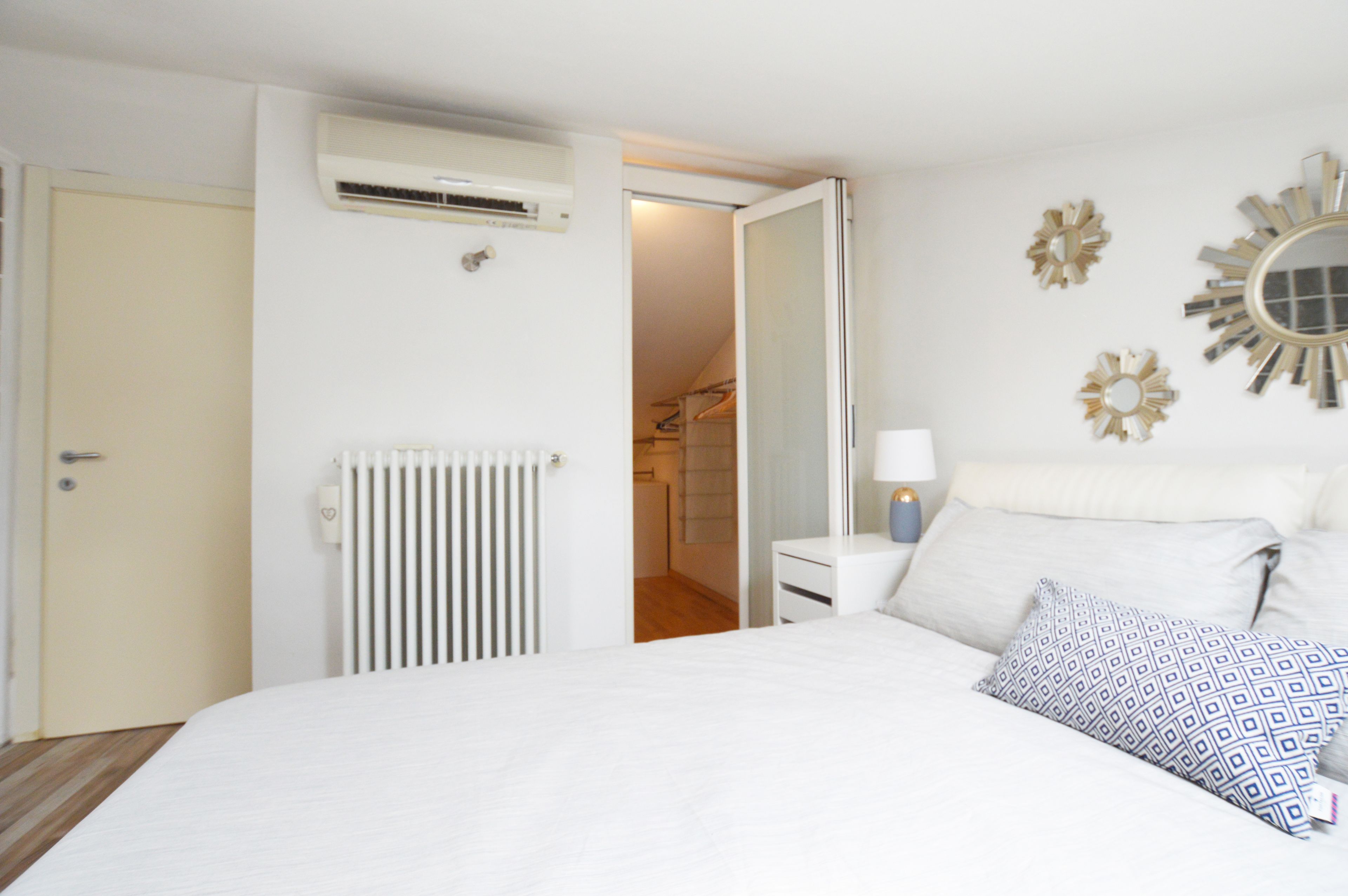 A bedroom with a bed, bedside table, lamp, and decorative mirrors.
