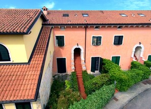 A building with a red-tiled roof, arched doorways, and green shutters. - Salionze - Via Benaco 80 (Valeggio sul Mincio)