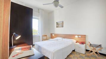 A neatly arranged hotel room with a bed, bedside lamps, a desk with a lamp, a chair, and a small table.