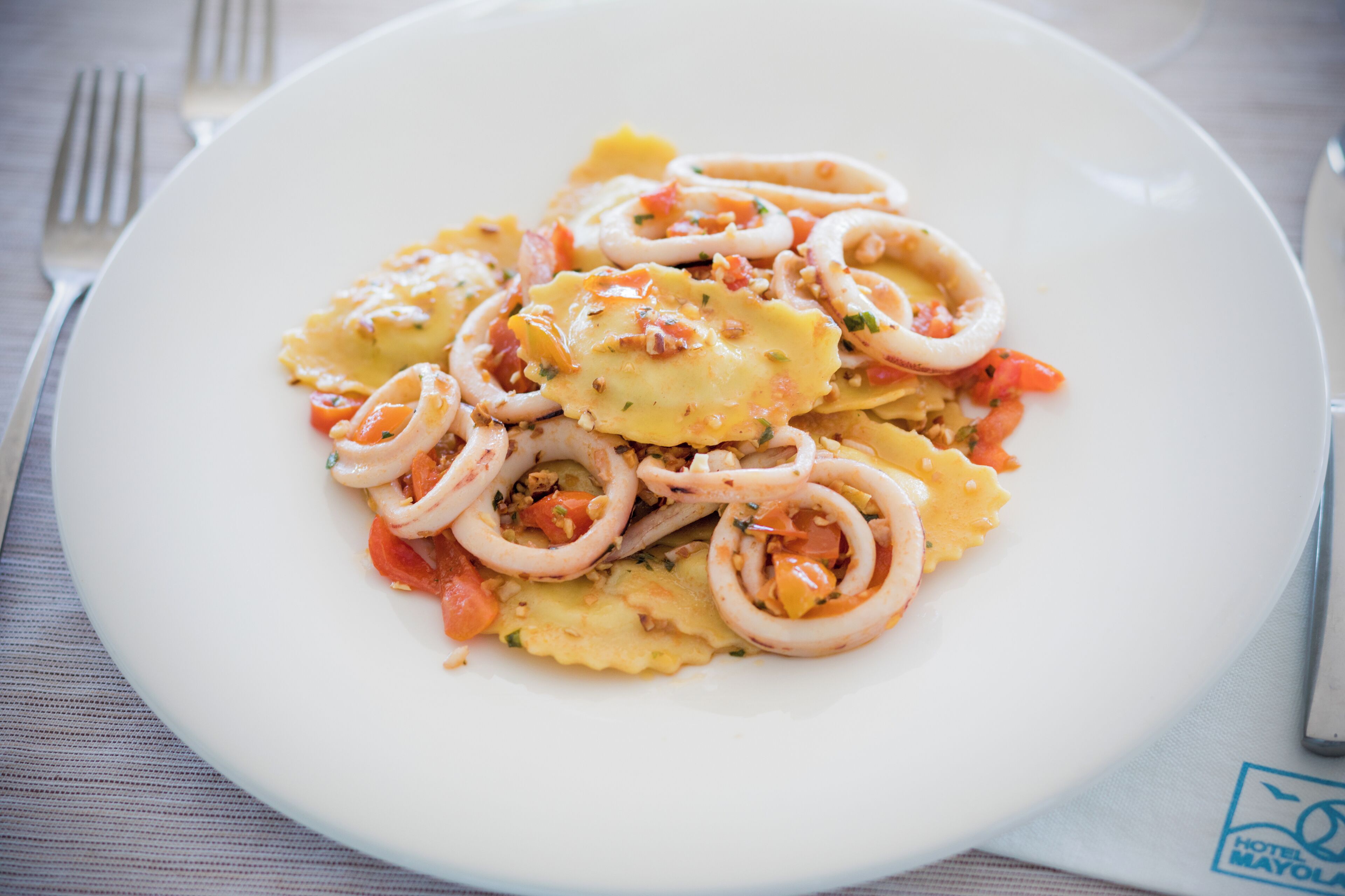 A plate of pasta with squid rings and diced tomatoes.