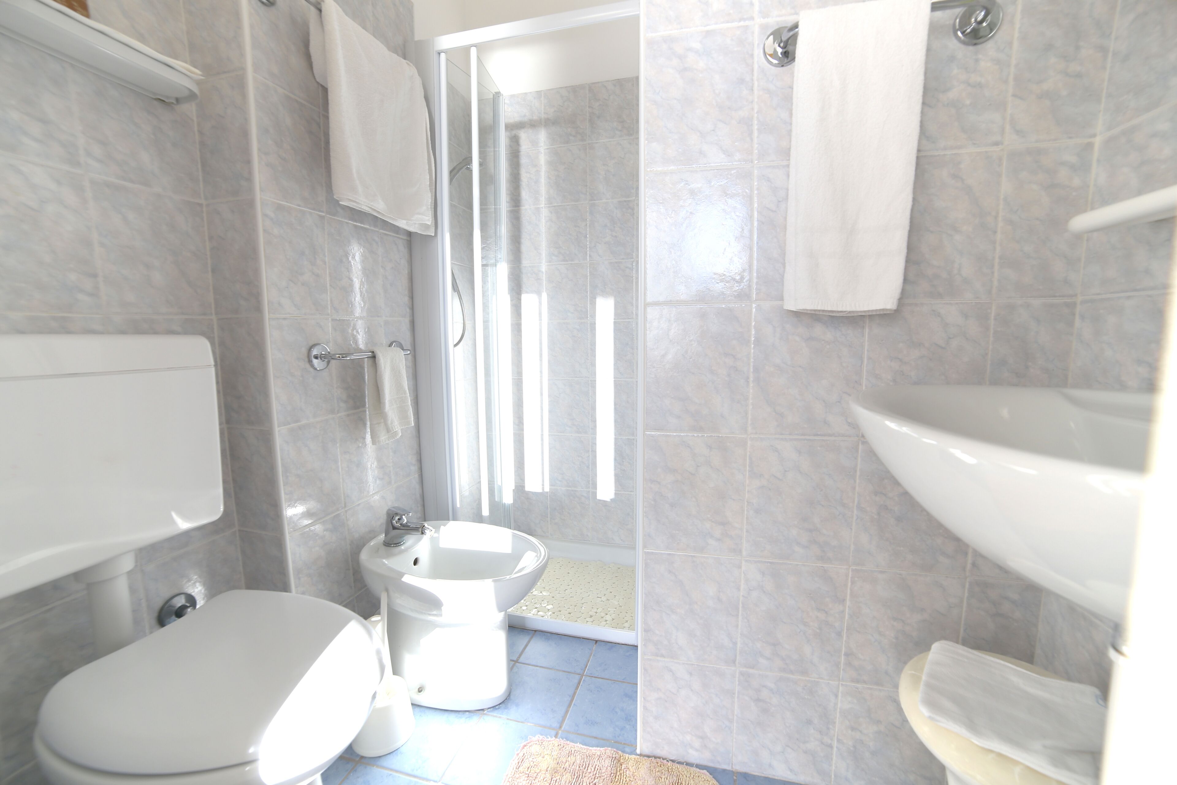 A bathroom with a toilet, bidet, and sink, all in white.