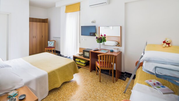 Une chambre d’hôtel avec deux lits, un bureau, une chaise, une télévision et une armoire.