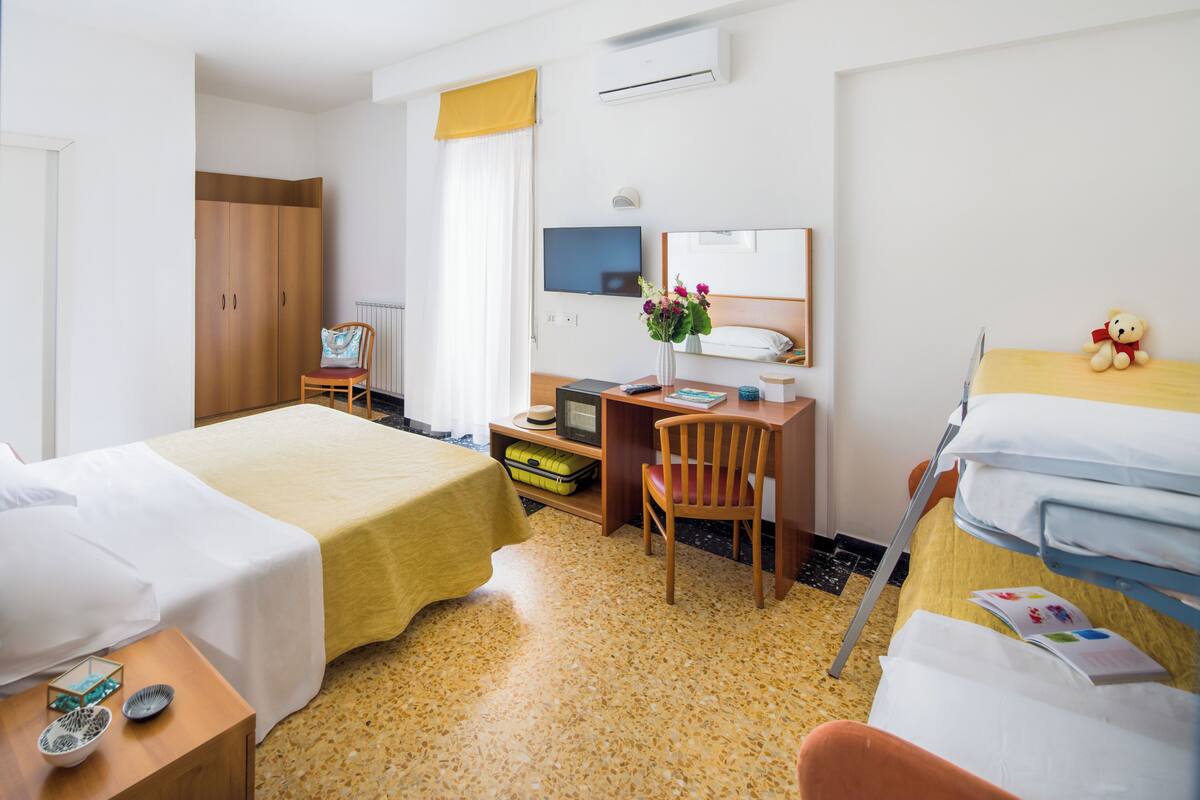 Een hotelkamer met twee bedden, een bureau, een stoel, een televisie en een kledingkast.