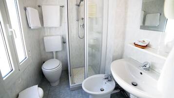 Un baño moderno con inodoro, bidé, cabina de ducha y lavabo.