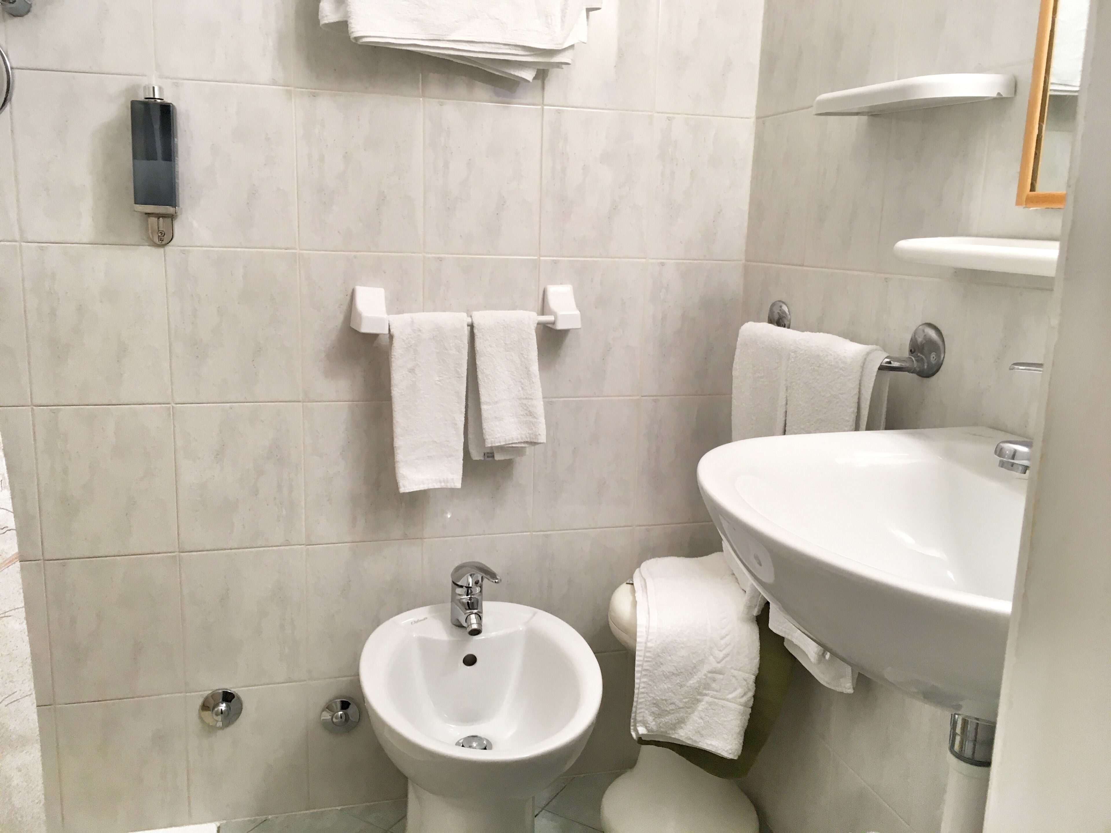 A bathroom with a bidet, a sink, and two towels hanging on the wall.