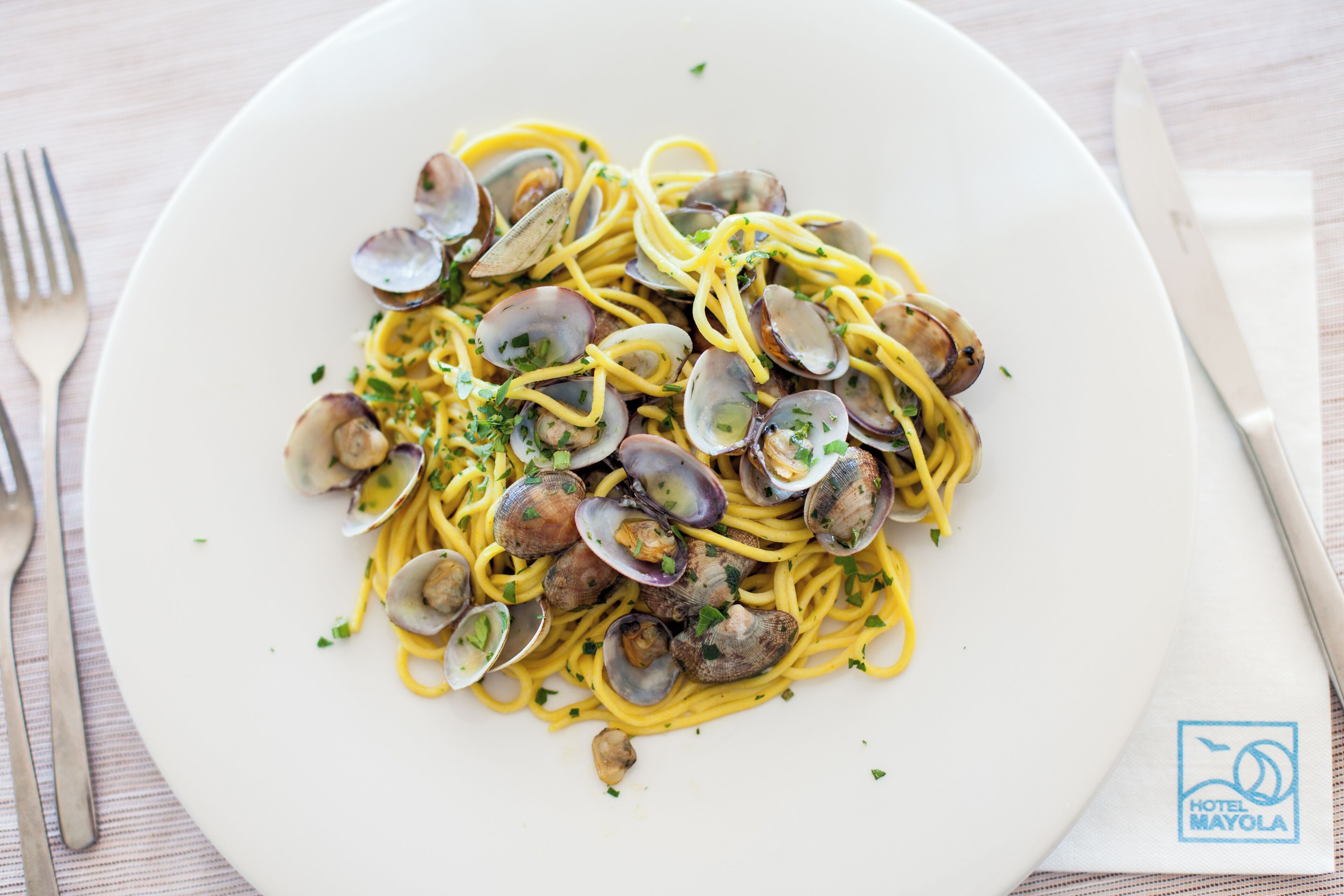 Un plato de espagueti con almejas, decorado con hierbas.