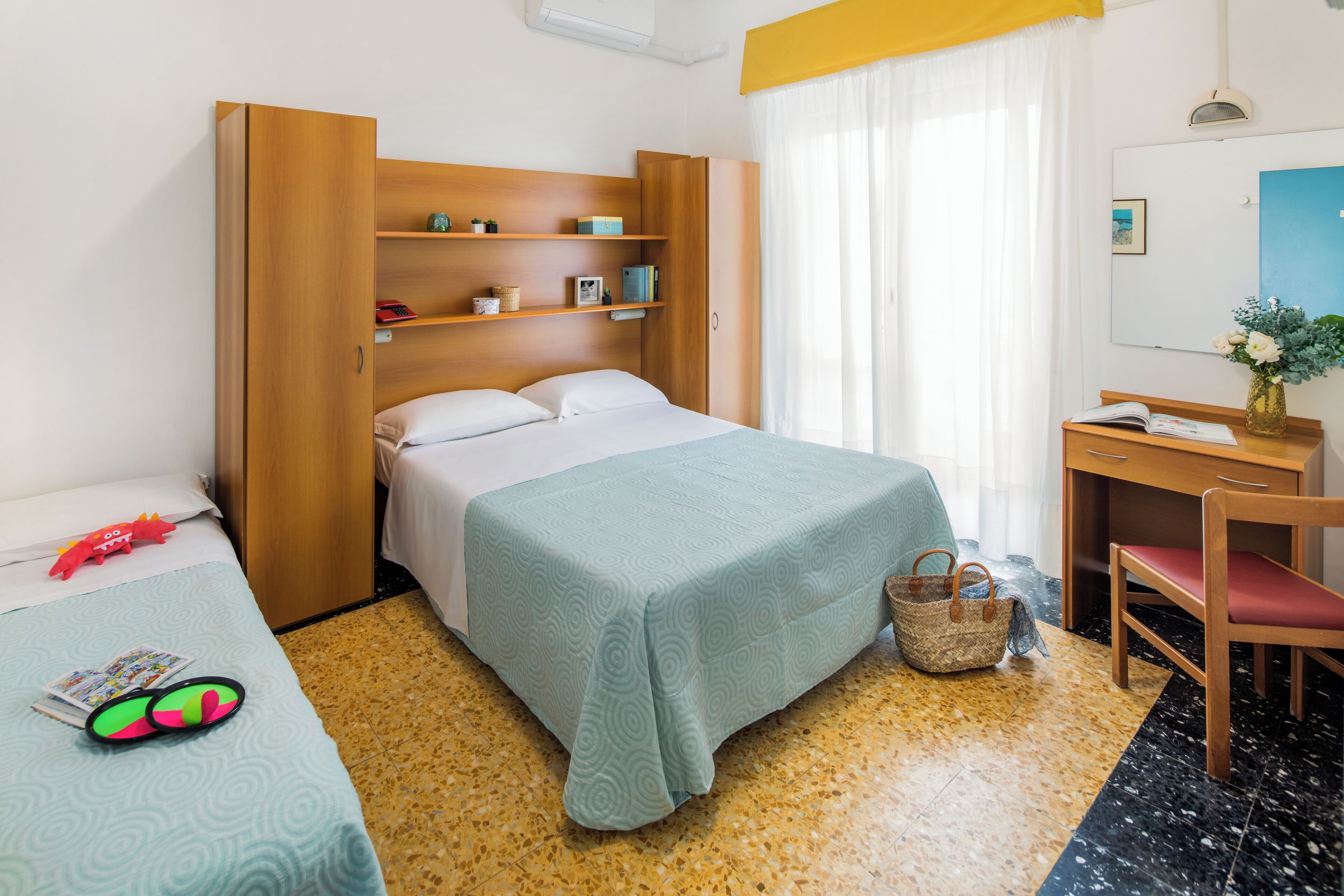 Ein Hotelzimmer mit einem Bett, einem Schreibtisch, einem Stuhl und einem kleinen Tisch mit einer Vase.