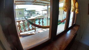 A view from a room with a wooden window sill, looking out to a balcony with a rope barrier and a railing. - Koko Acqua Lodge (Bocas del Toro)