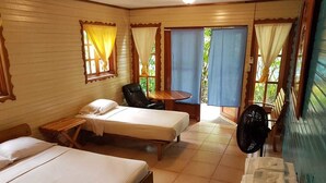 A hotel room with two single beds, a small table, a chair, and a fan. - Koko Acqua Lodge (Bocas del Toro)