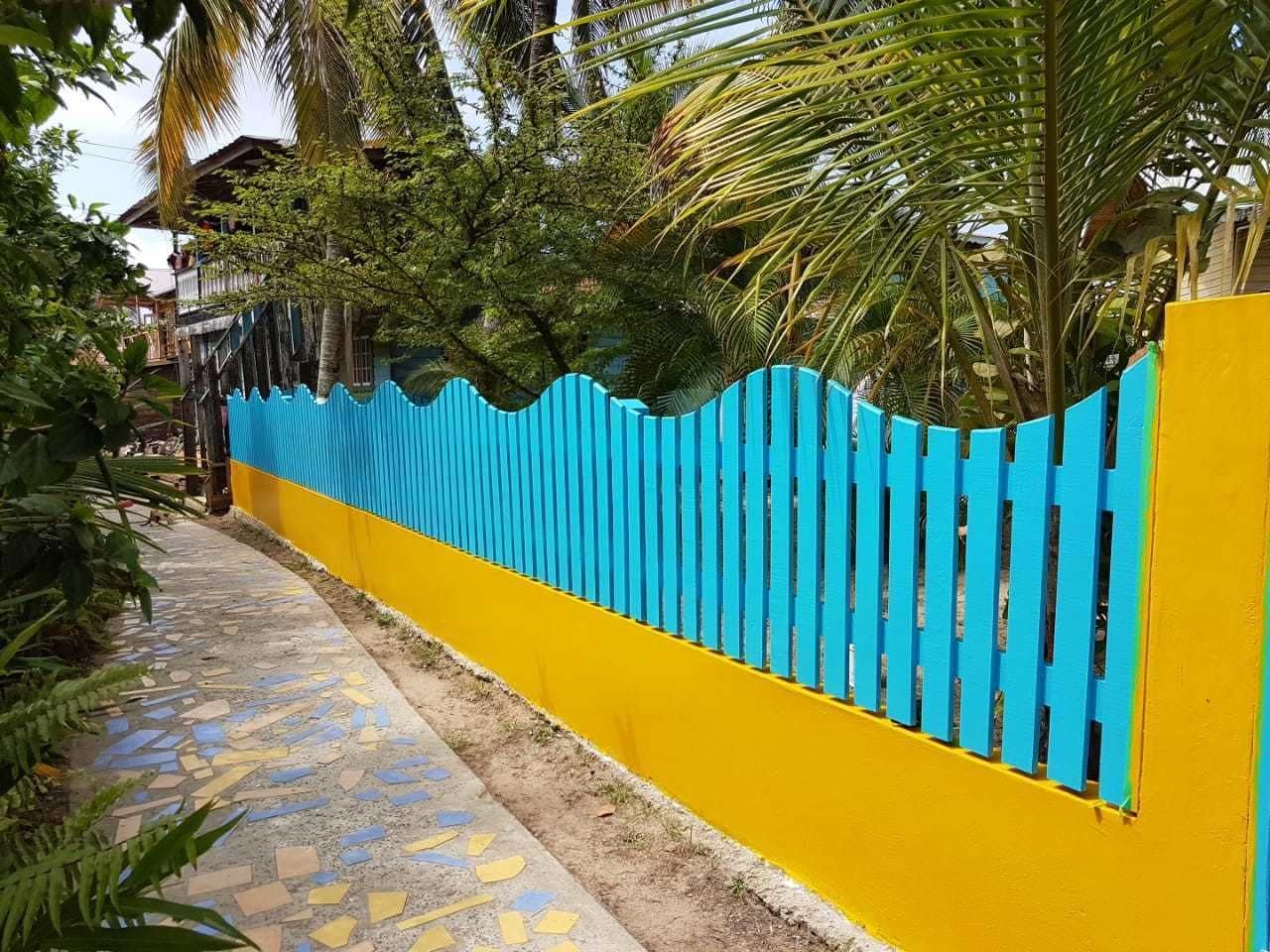 A pathway leading to a building with a blue and yellow fence.