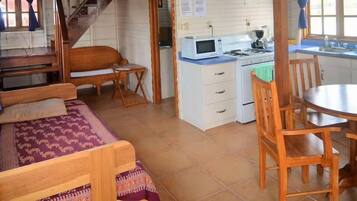 Een gezellige, meerlaagse kamer met een trap, een kitchenette, een eethoek en een zithoek met een kamerbreed tapijt.