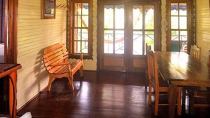 A dining area with wooden furniture, a ceiling fan, and large windows. - Koko Acqua Lodge (Bocas del Toro)