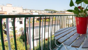 A balcony with a view of a cityscape, a red potted plant, and a wooden bench. - Civico 364 (Naples)