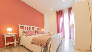 A bedroom with a bed, bedside tables, a nightstand, a window with curtains, and a door. - Civico 364 (Naples)