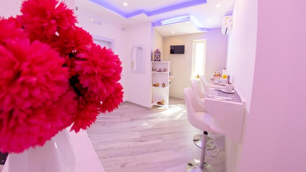 A modern interior with a white reception desk, a white chair, and a decorative vase with red flowers. - Civico 364 (Naples)