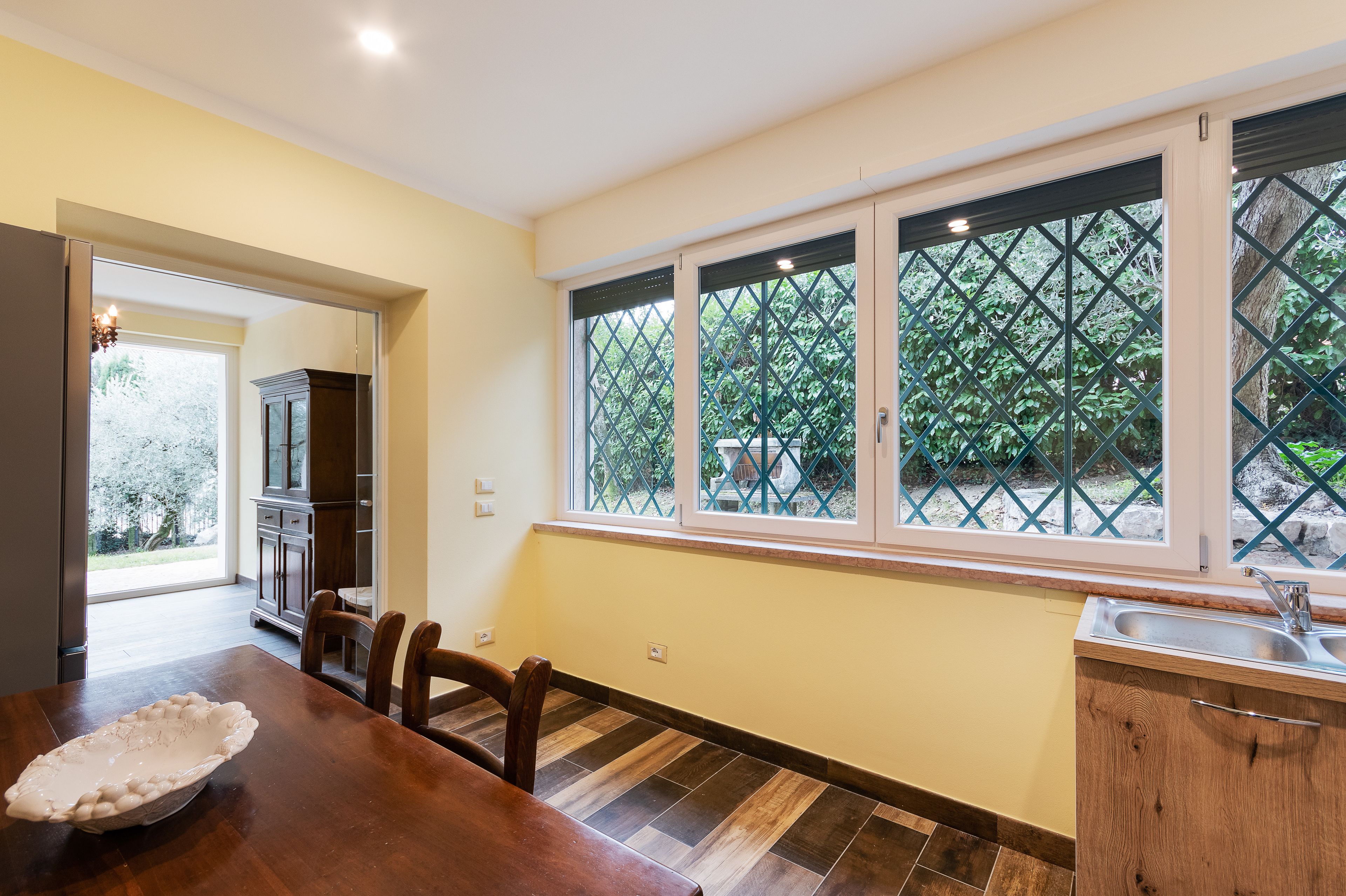 A kitchen with a dining area, a large window with a view of greenery, and a built-in sink.