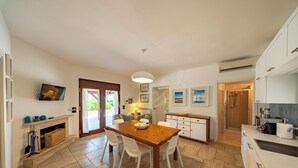 A spacious kitchen with a dining area, a fireplace, and a view through the glass door.