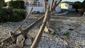 A house with a white exterior, a balcony with a railing, and a gravel driveway. - Villa Amarc: Family Fun, Kite Surf, Balcony View minutes to Rodgers/Baby Beach! (San Nicolas)