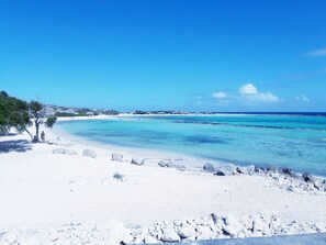 A beach with clear turquoise waters, white sand, and rocky outcrops.