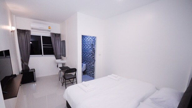A hotel room with a bed, a desk, a chair, a sink, and an air conditioning unit. - U-need Guesthouse (Bangkok)