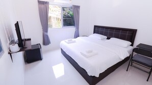 A modern hotel room with a large bed, a desk with a computer, and a window with curtains. - U-need Guesthouse (Bangkok)