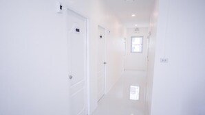 A bright, white hallway with doors numbered 401 and 402. - U-need Guesthouse (Bangkok)