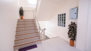A staircase with metal railings, a potted plant, and a wall-mounted air conditioning unit. - U-need Guesthouse (Bangkok)
