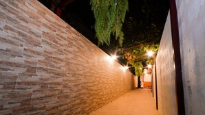 A corridor with brick walls and a tiled floor, leading to a door. - U-need Guesthouse (Bangkok)