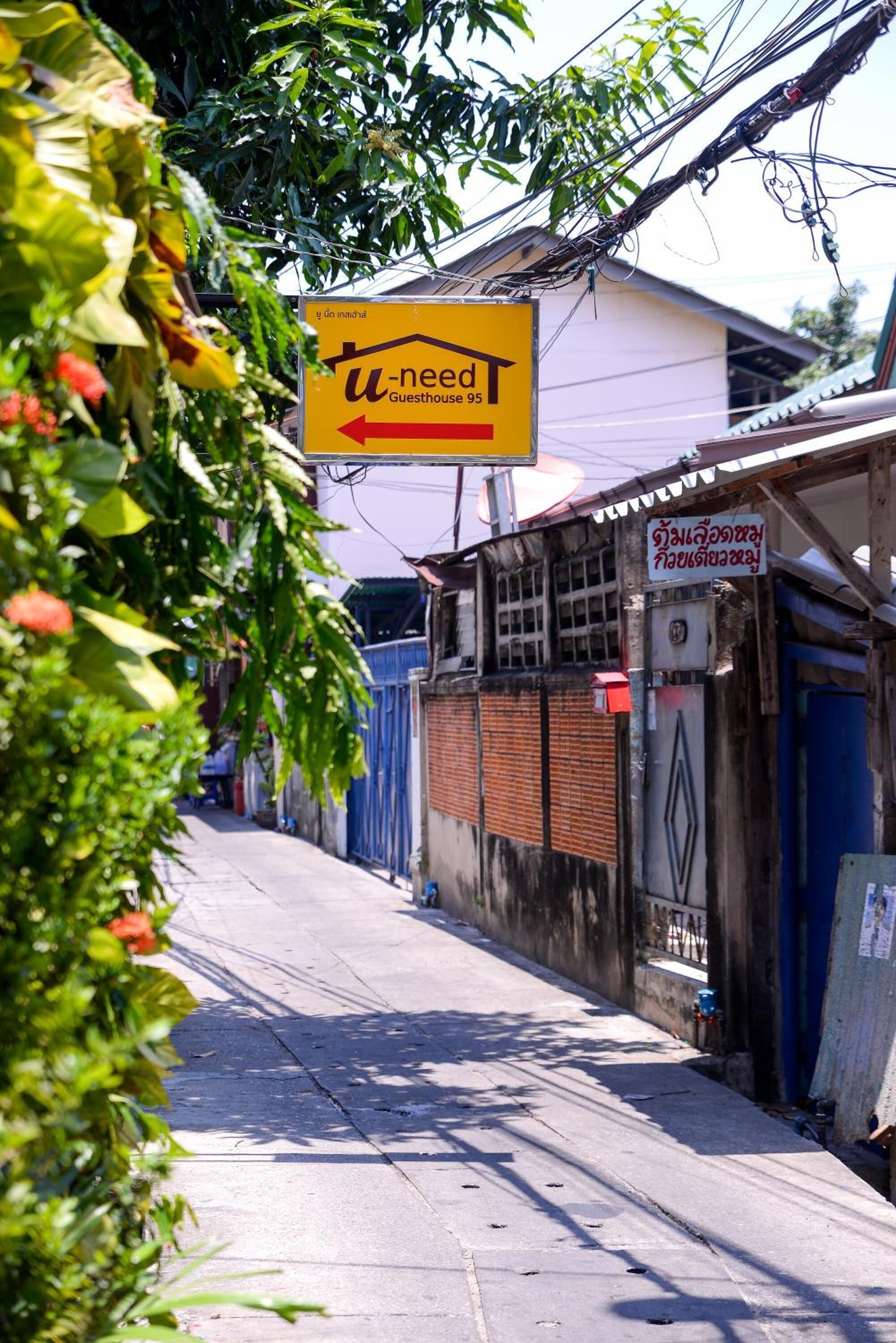 A narrow street with a yellow sign for a guesthouse.