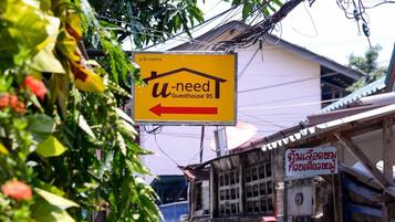 A narrow street with a yellow sign for a guesthouse.