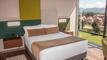 Un dormitorio moderno con una cama grande, vistas de la ciudad y una pared verde decorativa.