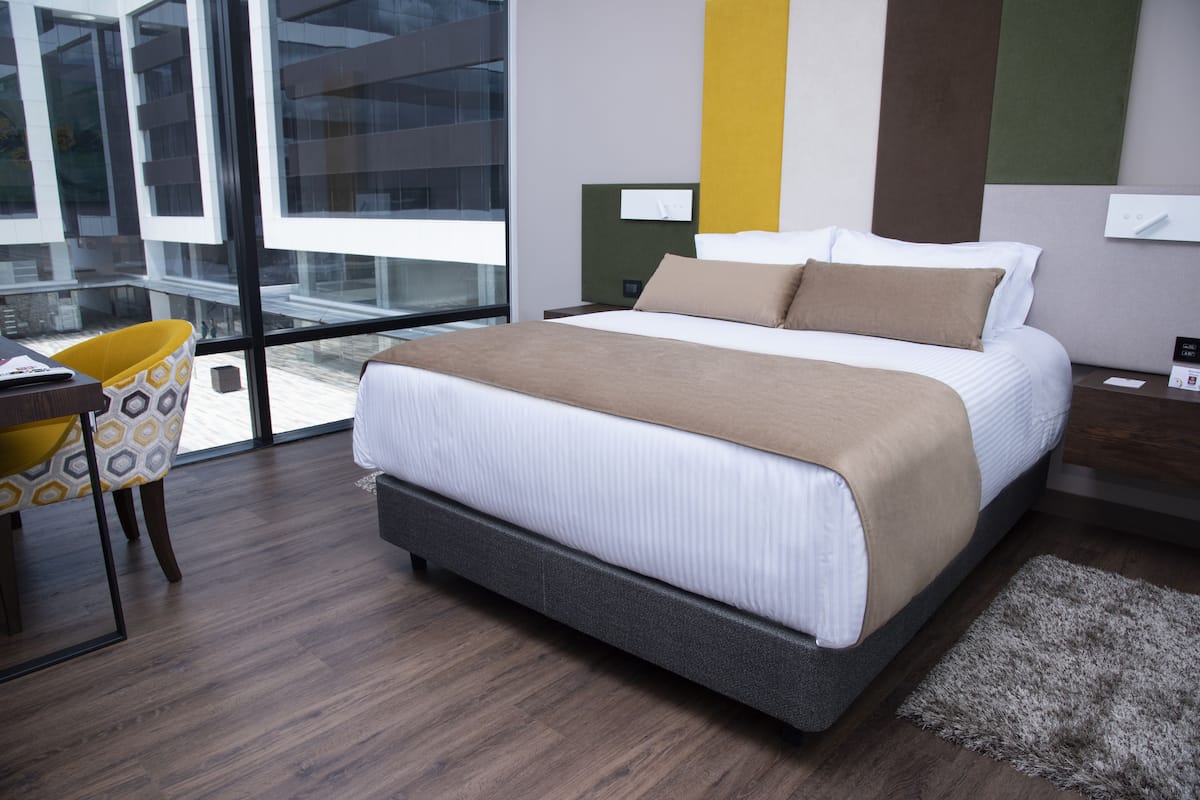 Una habitación de hotel moderna con una cama grande, un escritorio y una silla.