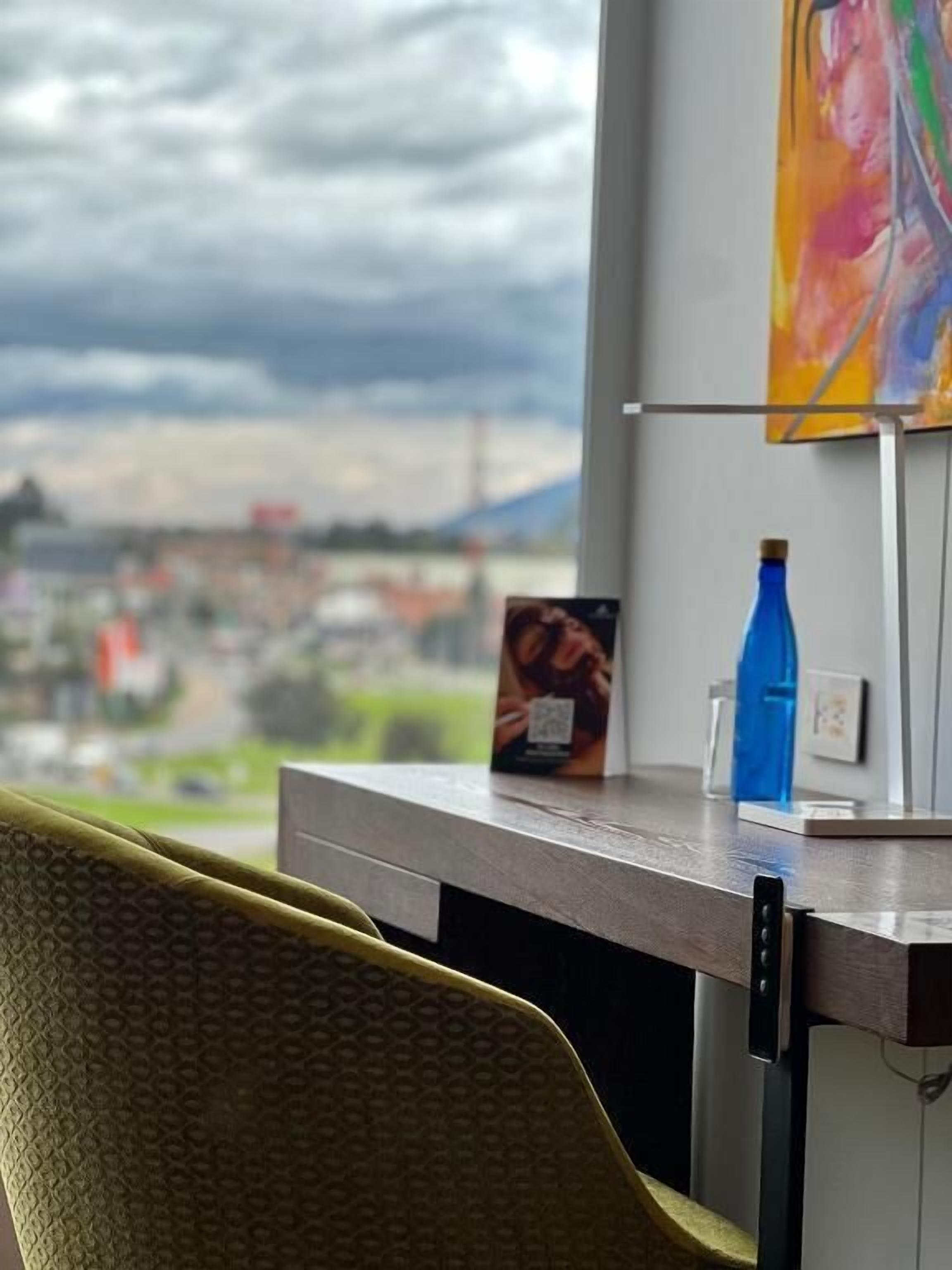 A view from a window with a table, a chair, and a painting on the wall.