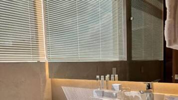Un baño moderno con un lavamanos grande de color blanco, un espejo y un inodoro.