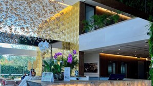 A modern reception area with a marble reception desk, a decorative wall with hanging elements, and indoor plants. - Hotel Sabana Park  (Cajicá)