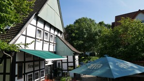 A traditional half-timbered building with a green awning and a blue umbrella. - Altes Farmhaus (Lienen)