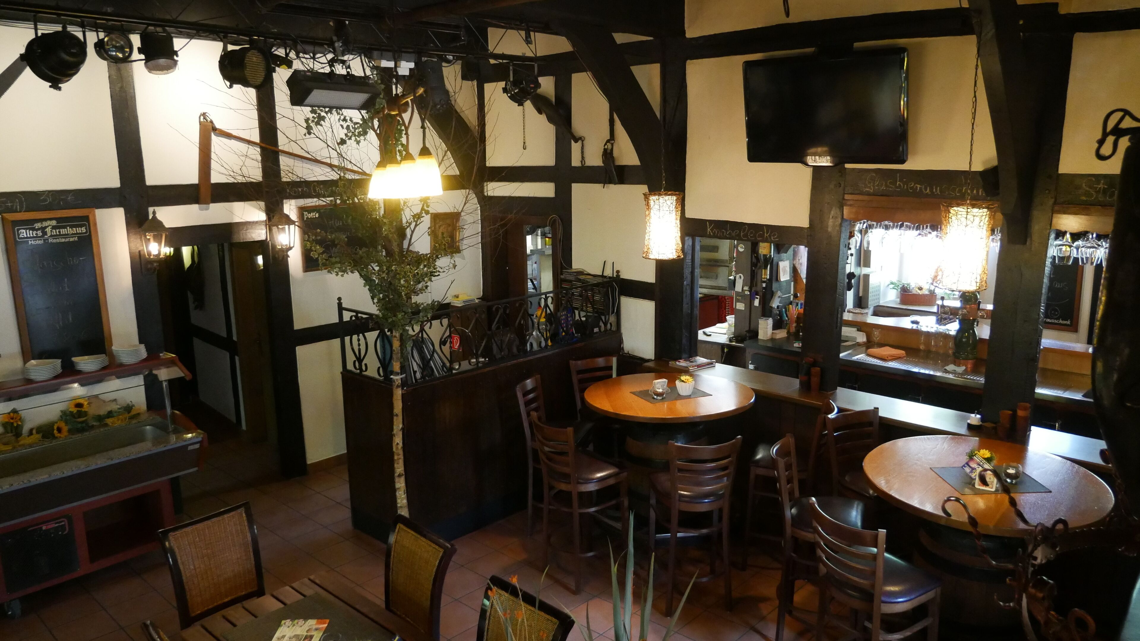 Un restaurante acogedor con muebles de madera, luces colgantes y una pizarra con el menú.
