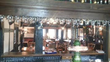 A bar area with a mirrored wall reflecting the interior, a green bottle labeled 'Pilsner', and a sign reading 'Glasbiere'.