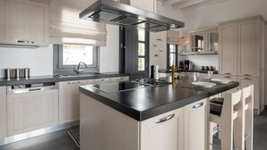 Een moderne keuken met een centraal eiland, inbouwapparatuur en kastjes van licht hout.