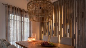 Een eethoek met een houten tafel, stoelen en een hangende lamp.