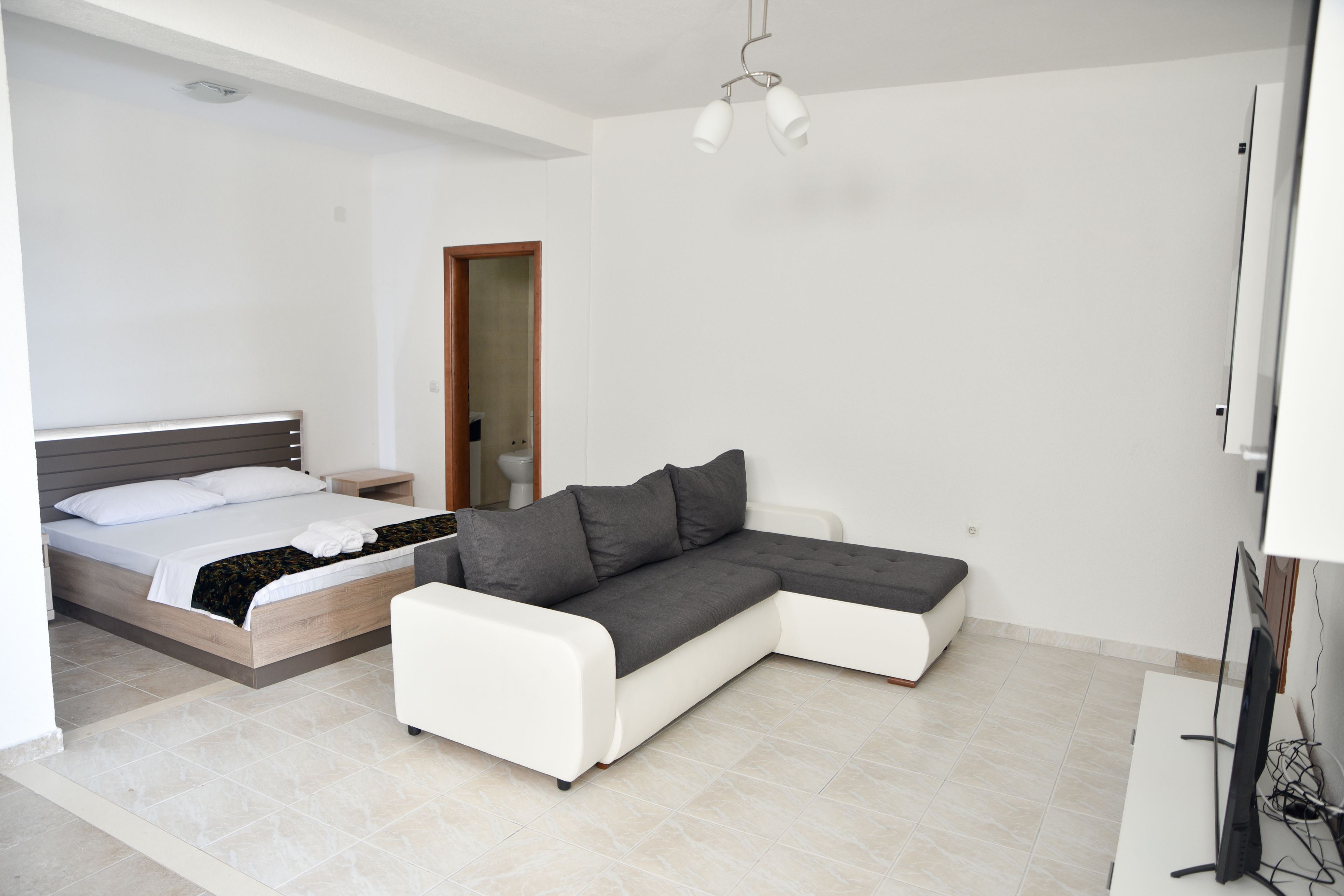 A modern bedroom with a bed, a white sofa, and a TV.