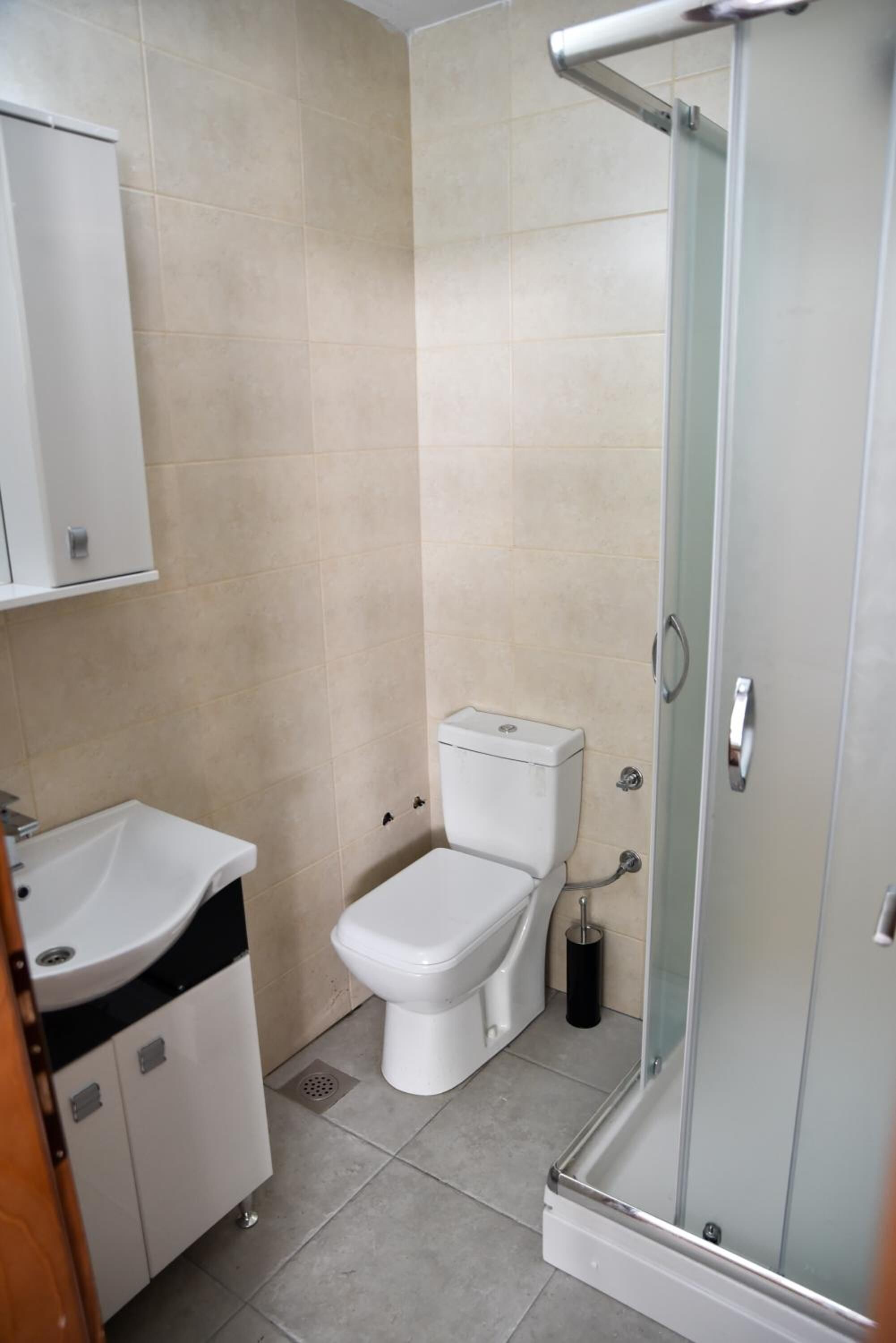 A bathroom with a toilet, sink, and glass shower enclosure.