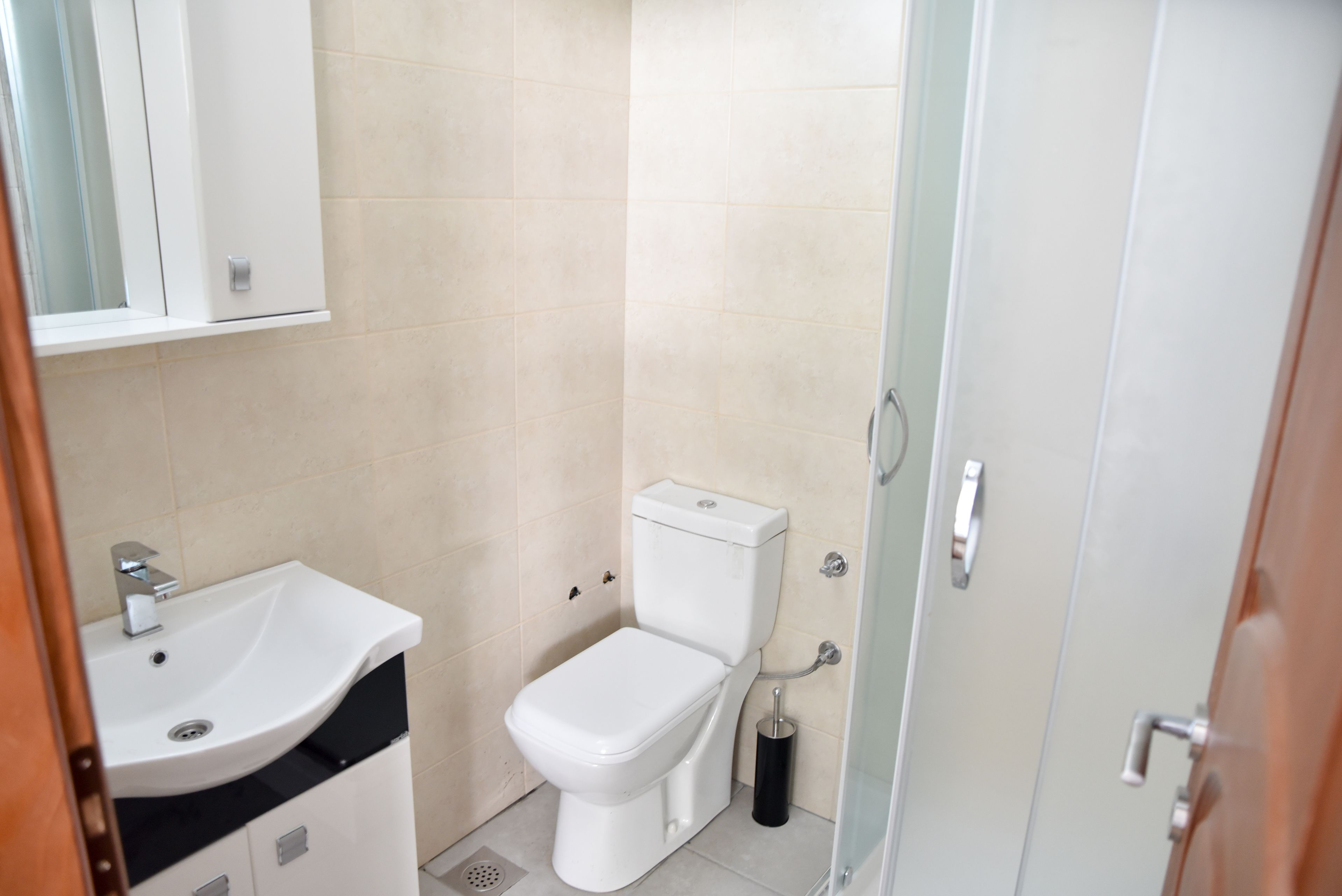 A small, clean bathroom with a white sink, toilet, and shower.