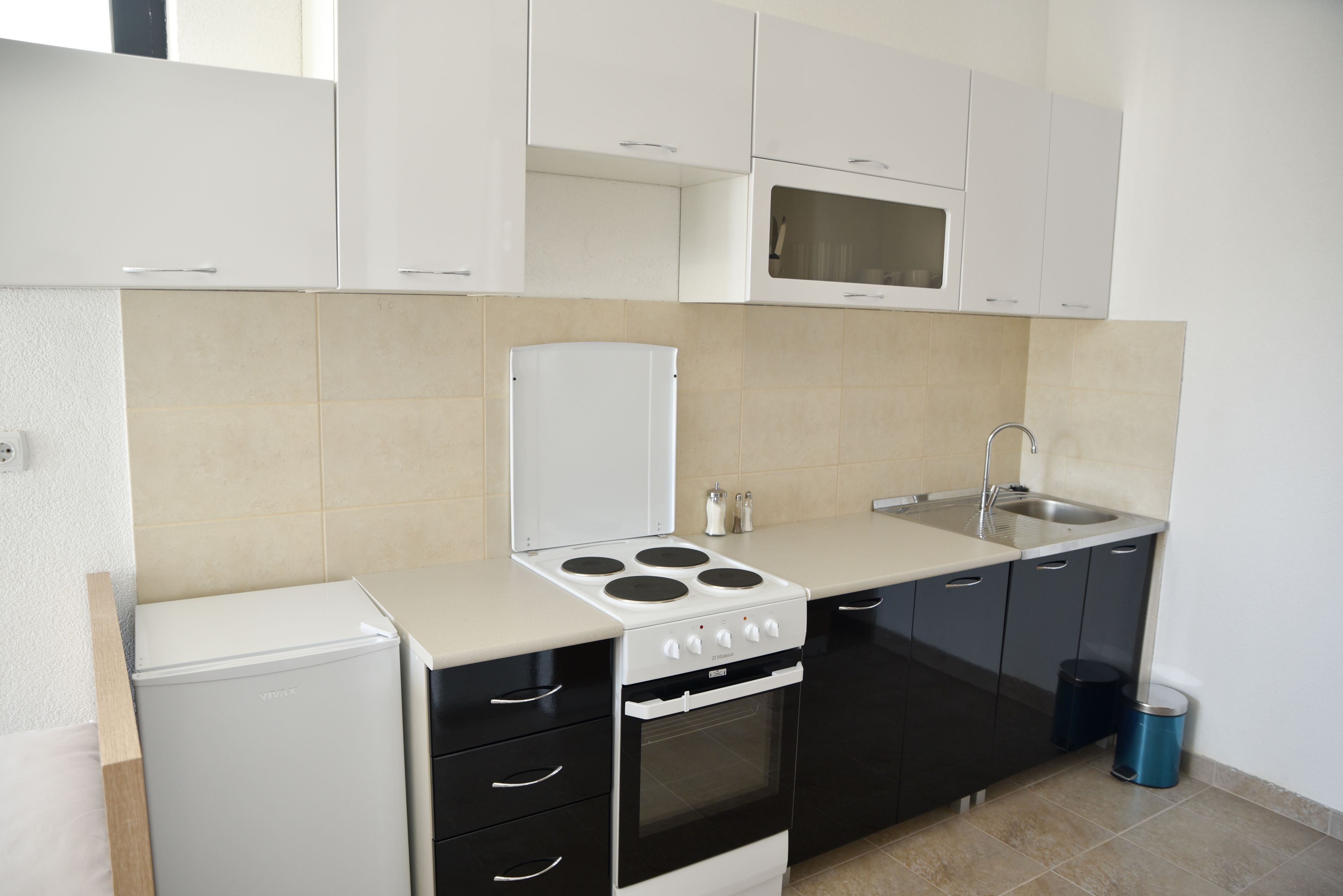 A compact kitchen with a refrigerator, stove, oven, microwave, sink, and cabinets.